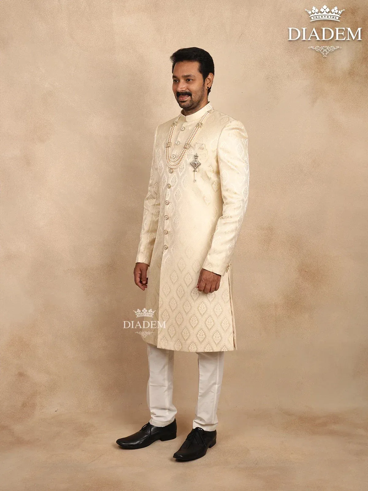 Cream Raw Silk Sherwani Suit Adorned with Floral Embroidery, Paired with Brooch and Bead Mala